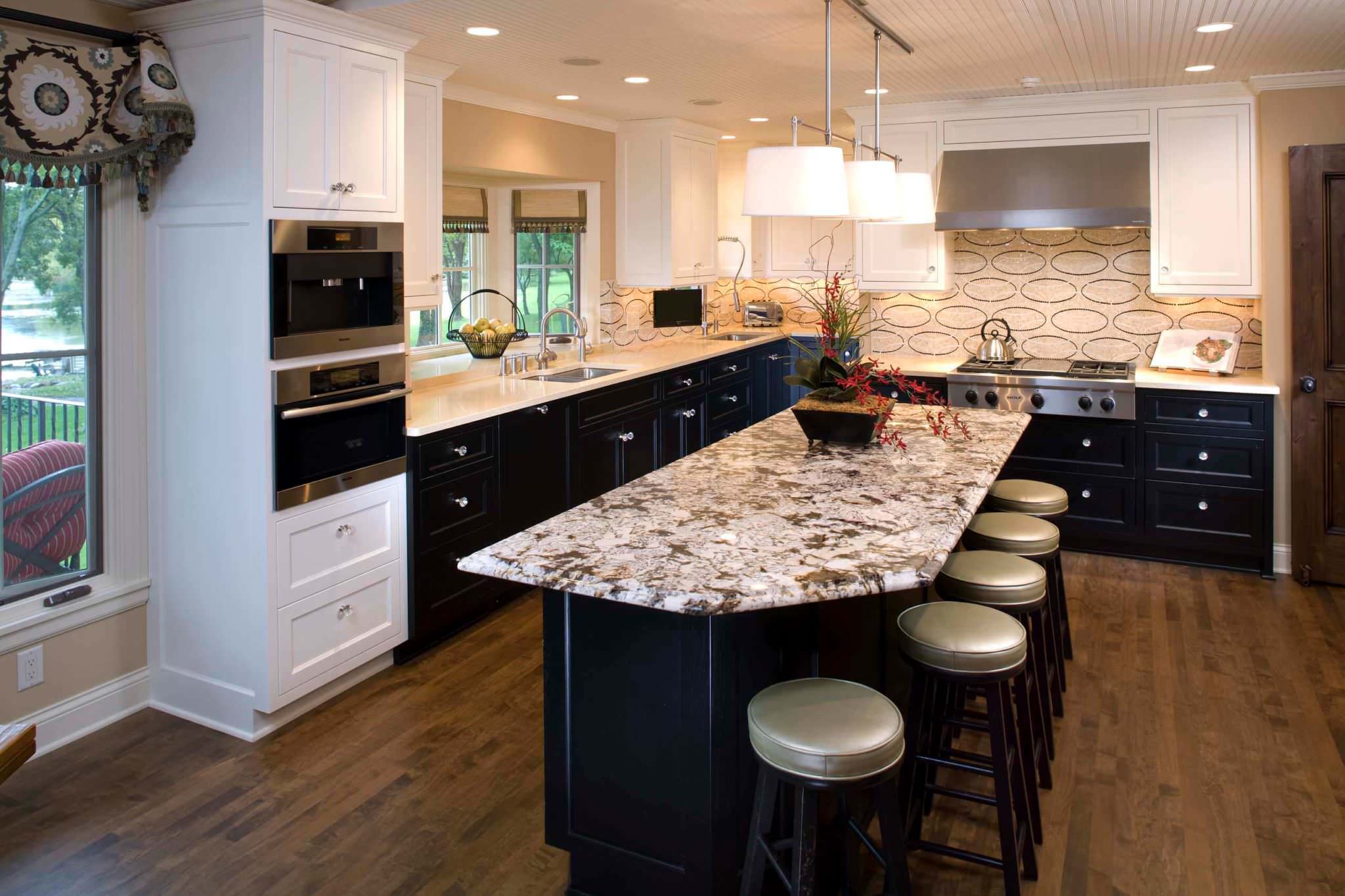 A luxurious cream colored kitchen with black granite counter tops,  stainless steel KitchenAid appliances and Edison bulbs above the island  Stock Photo - Alamy